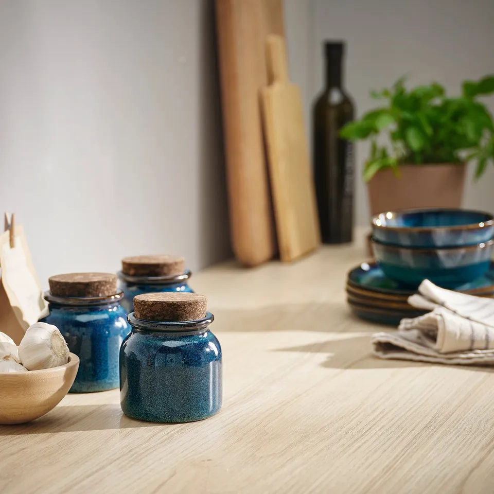 BRUGDHAJ blue jars, stoneware & cork, displayed with wooden bowls, bottles, & herbs.