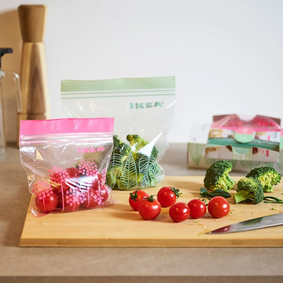 IKEA bags on kitchen counter with fresh vegetables. Bags resealable, holding tomatoes and broccoli, showing kitchen organisation.