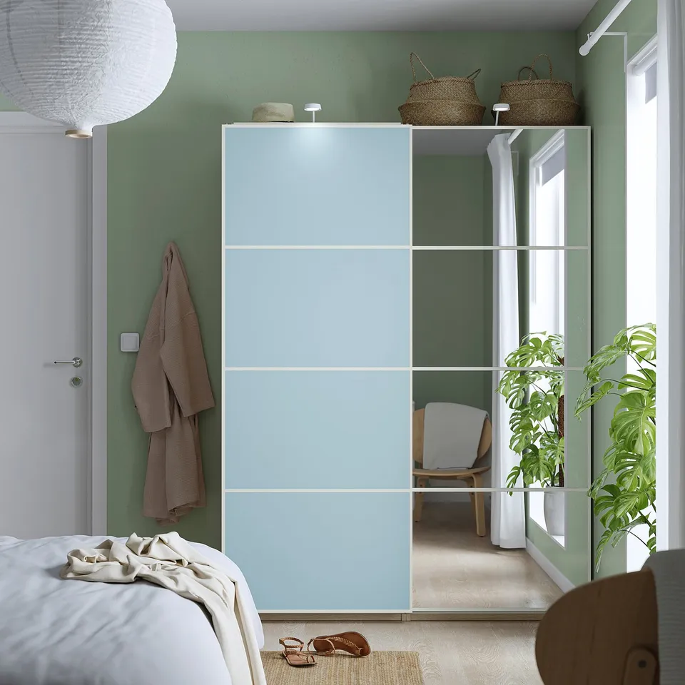 Light blue mirrored closet doors, modern, sliding, fit pax, with green walls, white bed, storage, plant, sandals.