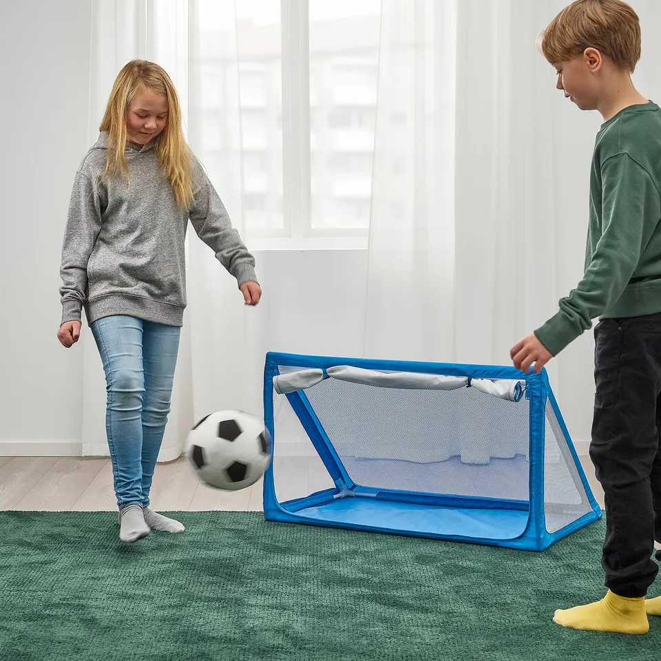 Two children playing indoor football with a SPORTSLIG ball storage goal, demonstrating its practical use for sports and storage.