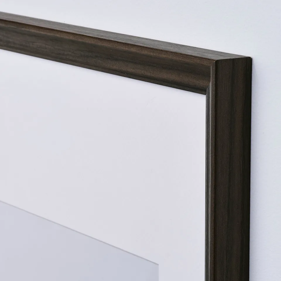 Snap a pic of a dark wooden picture frame. Slim profile, sturdy design. Handy wall mounts.