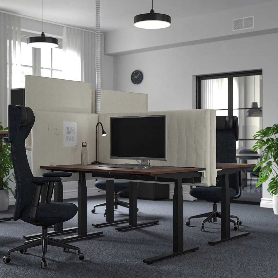Modern workspace MITTZON sit-stand desks, sleek black office chairs, and framed screens, arranged in a spacious, well-lit room.