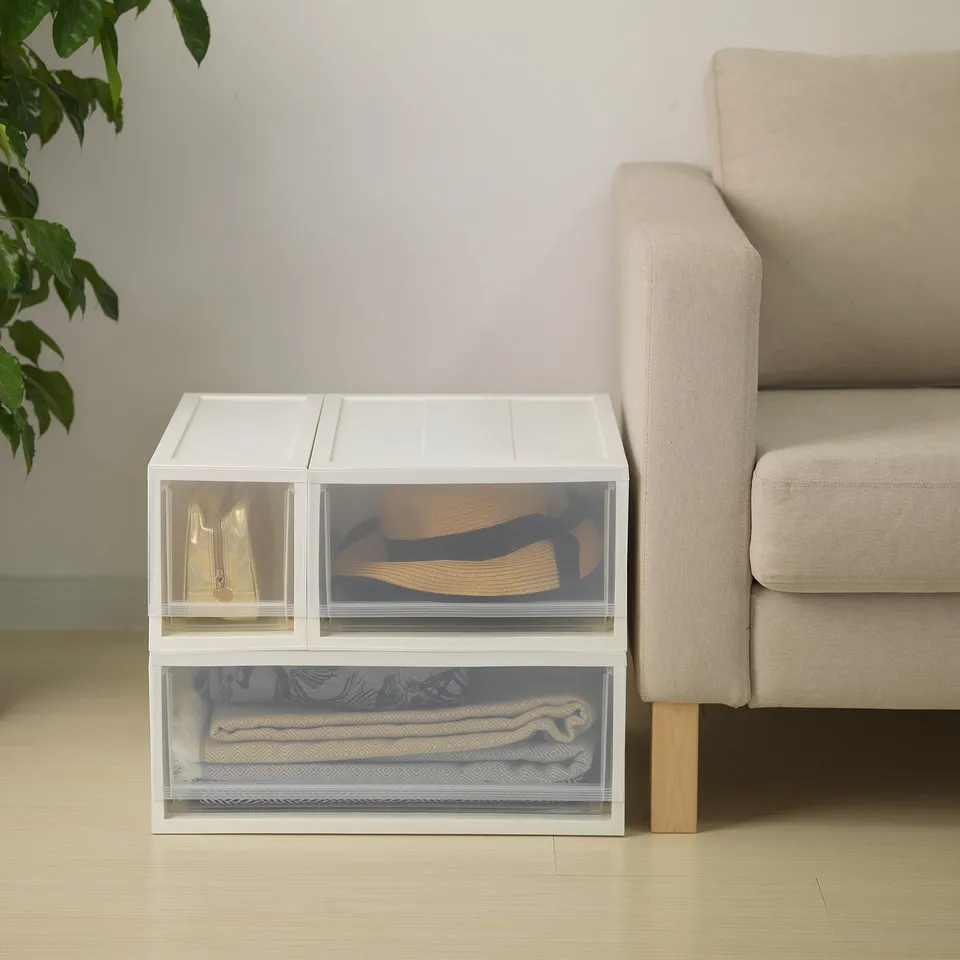 Clear storage drawers stacked, with a sofa nearby. Easy-to-pull drawers for organising items.