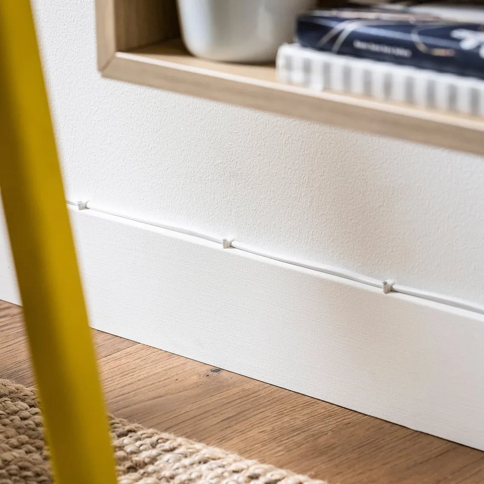 White TRIXIG toolbox on wooden floor, smaller than nearby books.