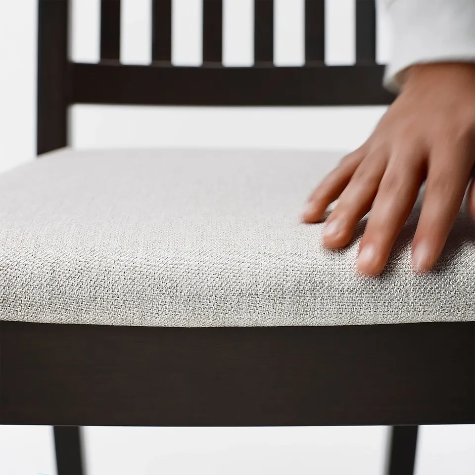 Hand resting on soft, upholstered chair cushion.