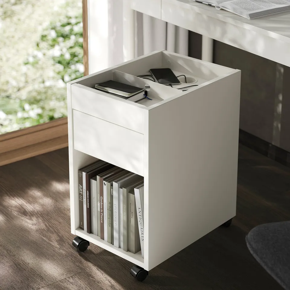 White rolling storage drawer unit, holding books and small items, ideal for organising workspace.