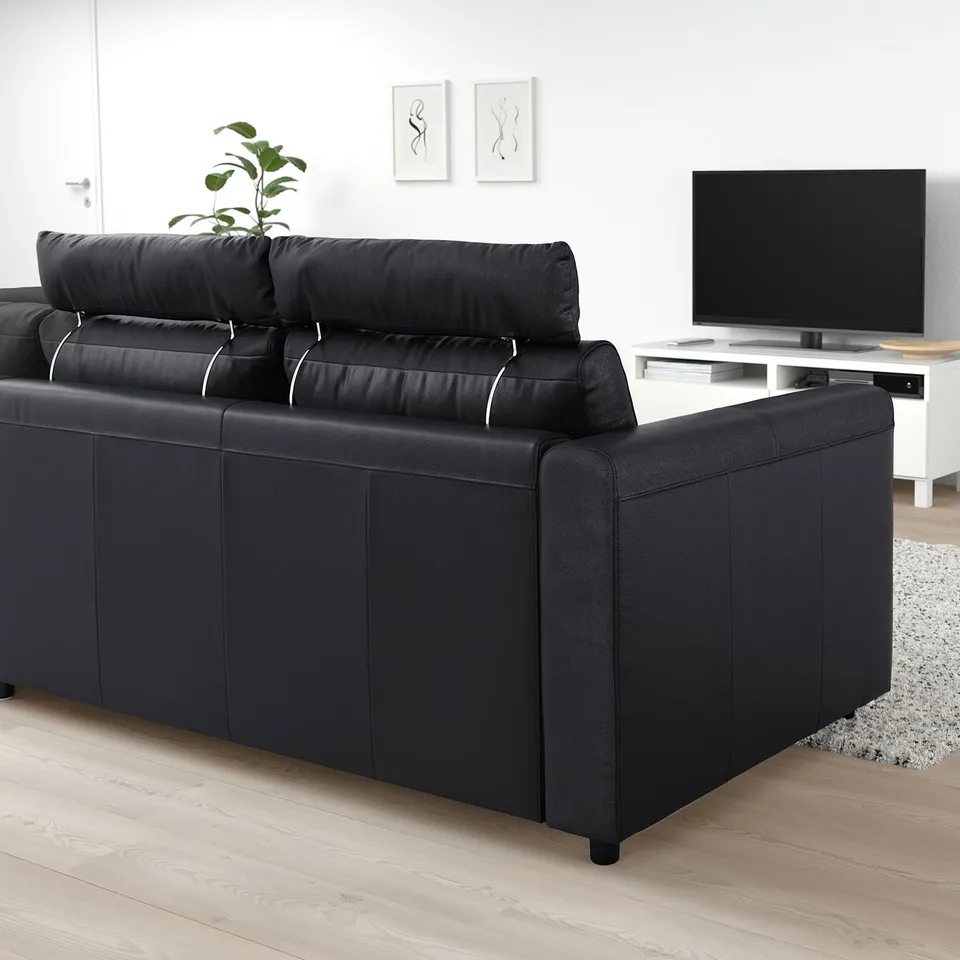 Modern black VIMLE sectional sofa against white walls, with tv and plant nearby. Sleek and spacious, designed for comfort with multiple cushions.