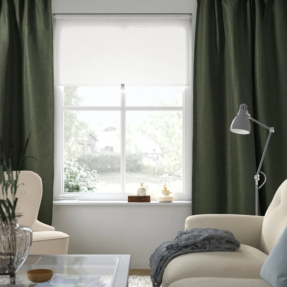 Modern living room with green curtains, white shade, and chair with throw.