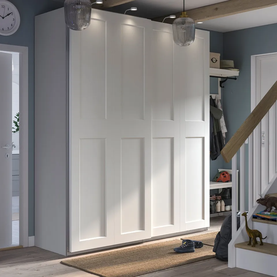 Modern white PAX wardrobe with sliding doors and built-in lighting, featuring a sleek, minimalist design.