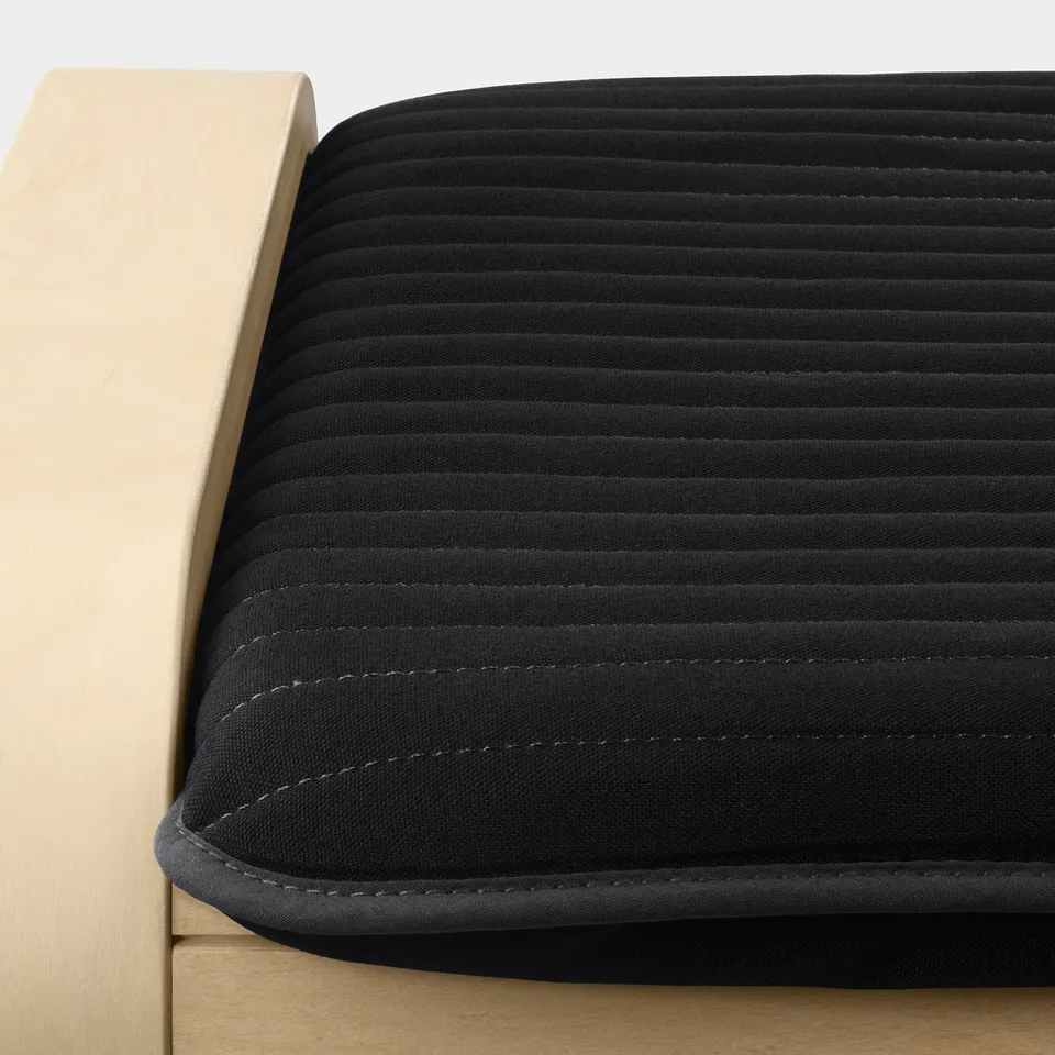 Close-up of a black, textured cushion on a wooden chair, showcasing its smooth fabric and stitching detail.