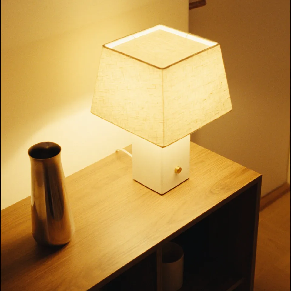 HALGATT lamp with white linen shade and ceramic base on wooden table, warm and inviting.