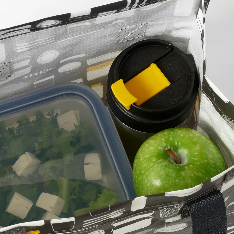 Insulated travel mug in a bag with blue container of greens and apple.