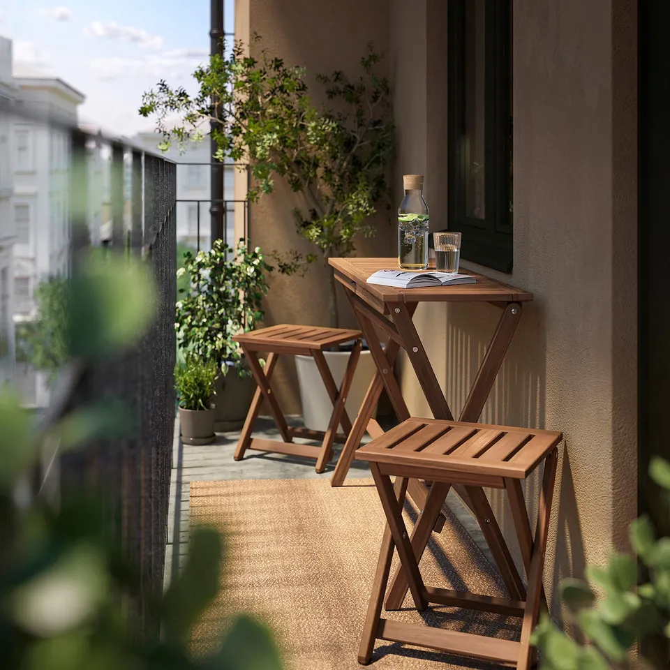 Balcony with brown wooden folding table and stools, glasses, and potted plants.