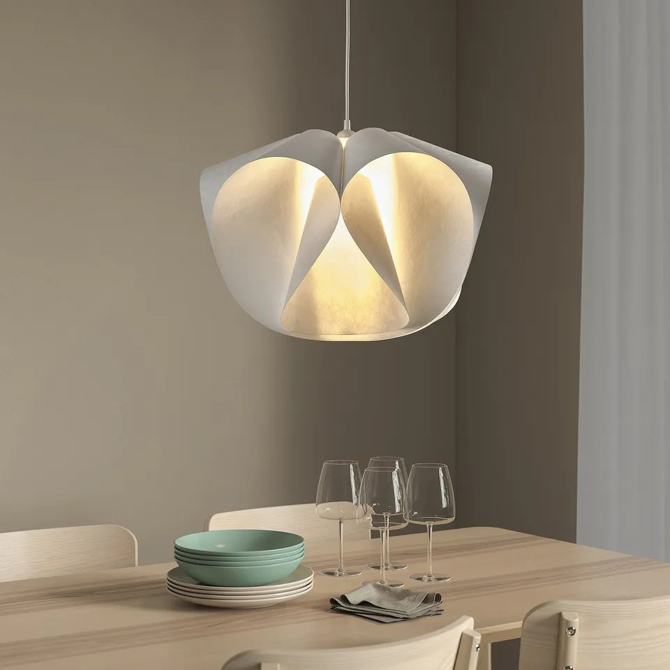 Large white pendant light, BÄCKNATE, hangs over wooden dining table with glasses, bowls, and plates.