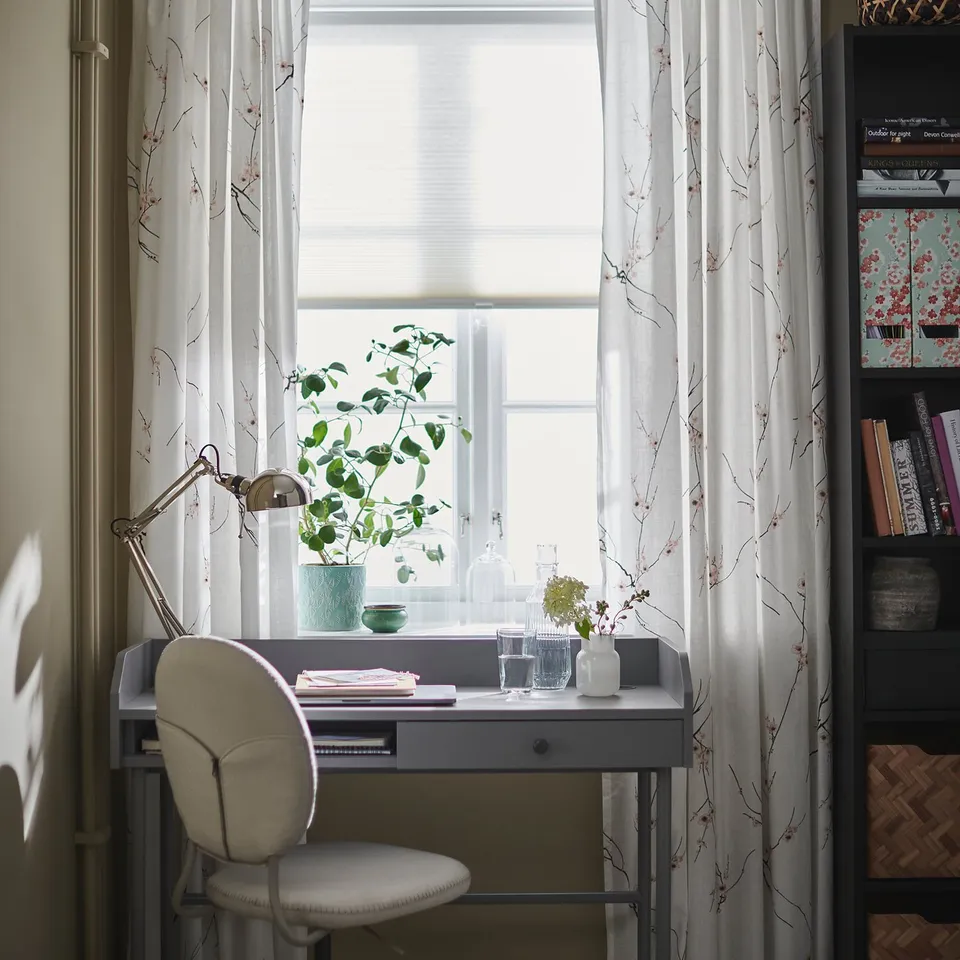 Cosy home office with grey chair, desk, lamp, plant by window.