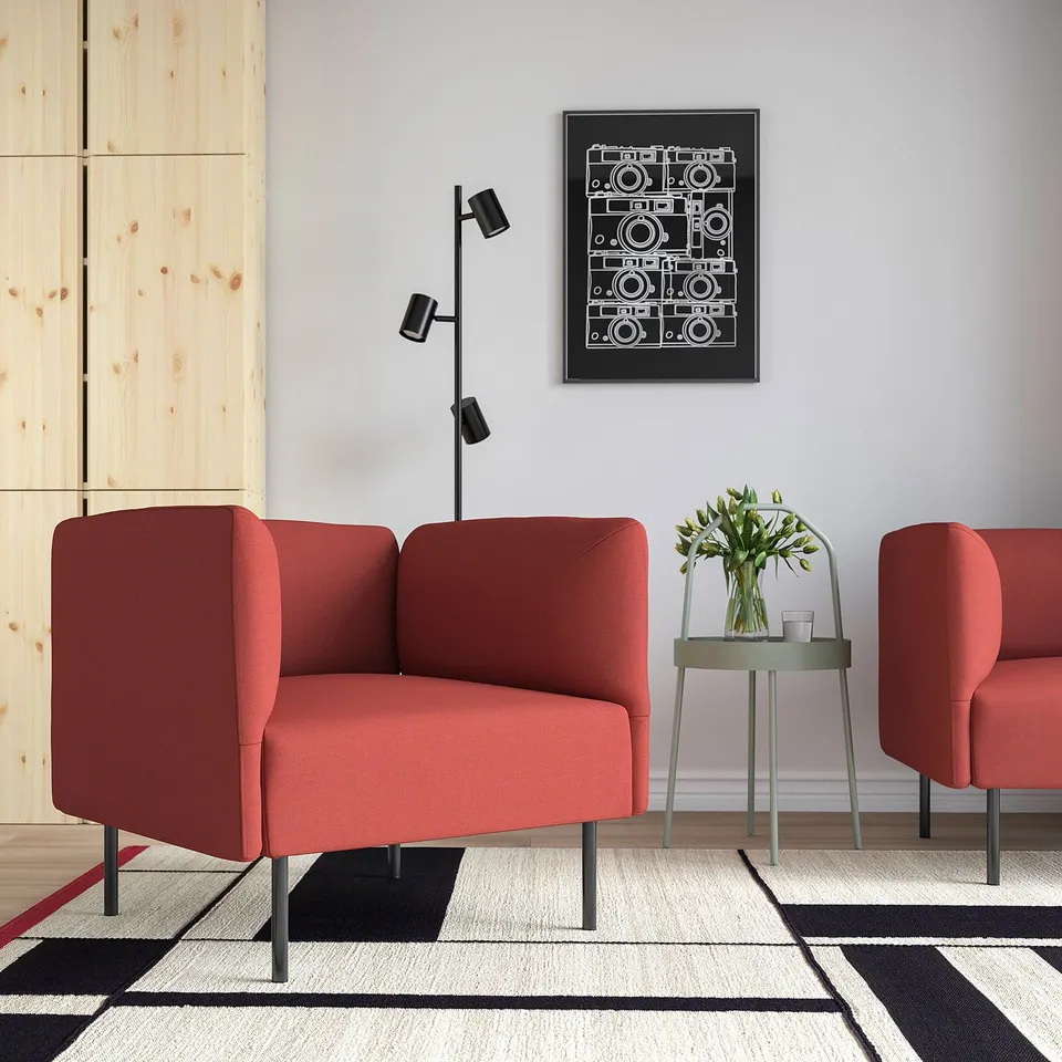 Modern living room with red LILLEHEM chairs, black-white rug, geometric art, side table with flowers.