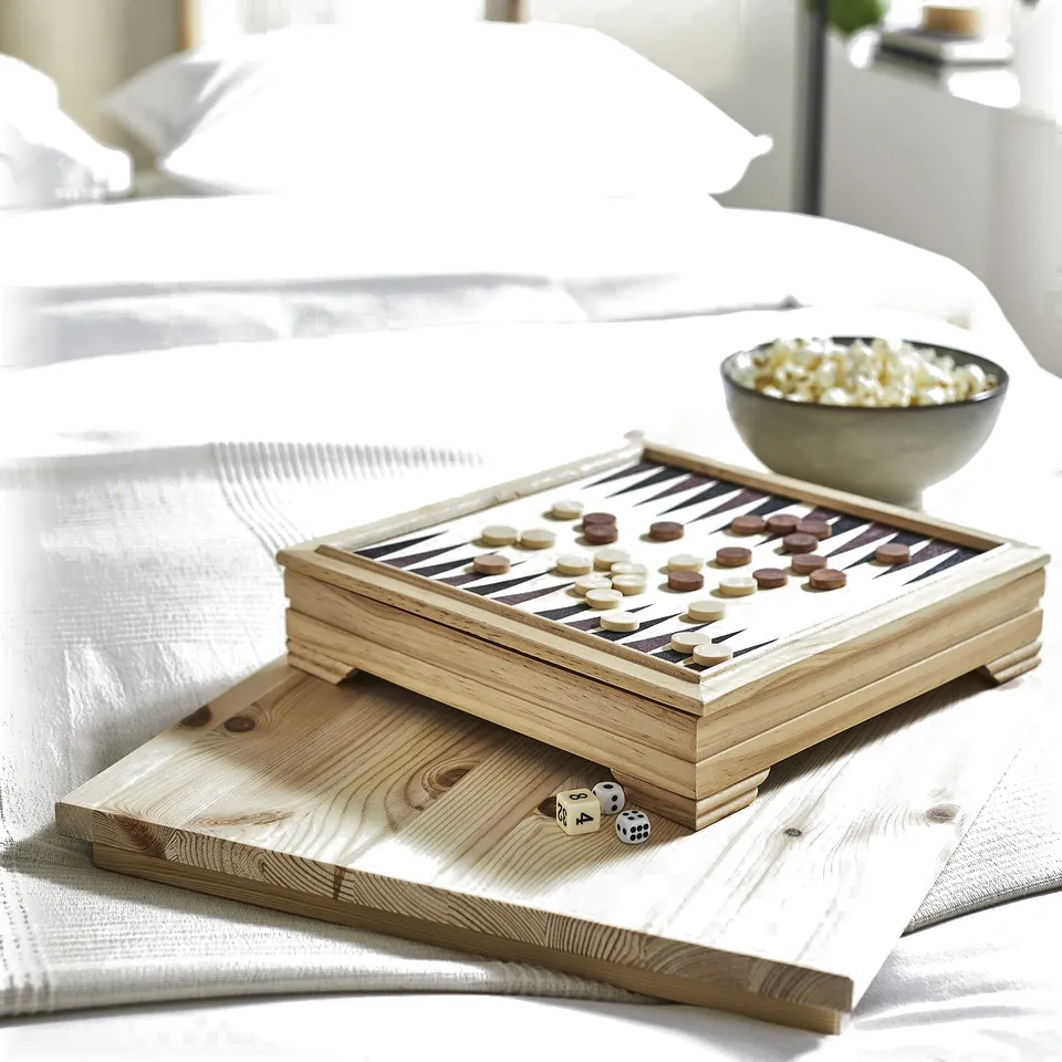 Wooden board game on bed with snacks. Game pieces and dice on tray. Neutral colours, cosy setting.