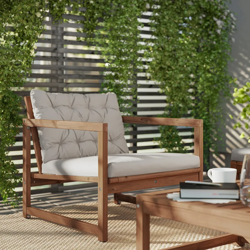 Modern outdoor lounge chair in brown acacia wood with light grey cushions. Comfortable and stylish for relaxation.