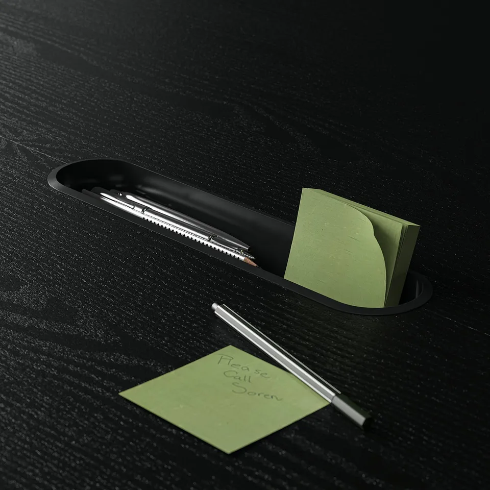 Black desk organiser with pens and green sticky notes. One note reads, please call boren.