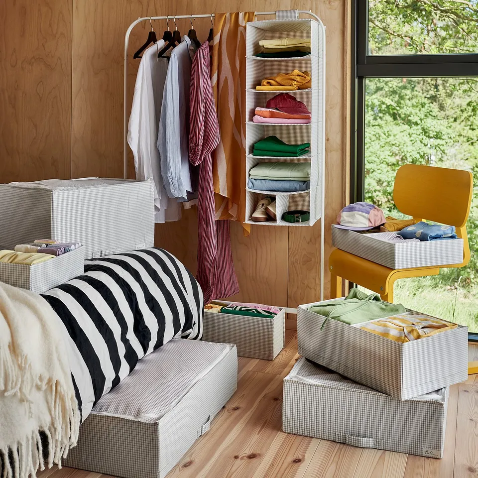 Room with wooden walls and floor, featuring storage boxes and a hanging clothes organiser.