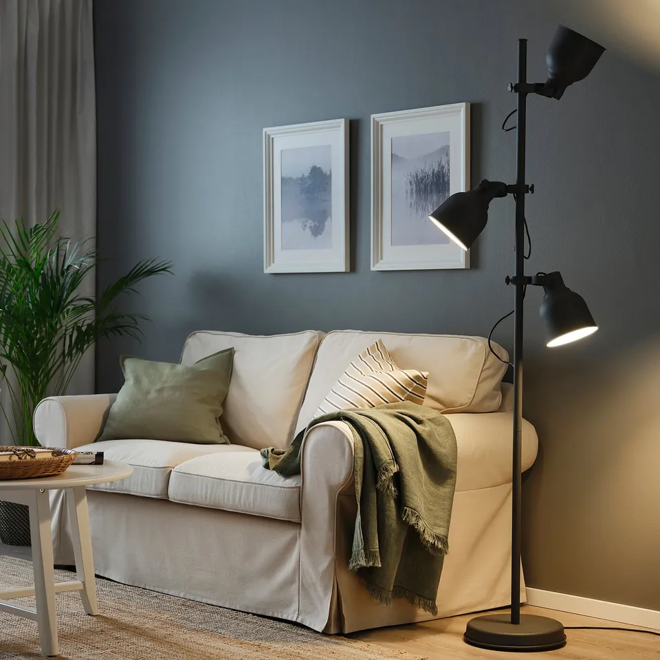 Cosy living room with beige sofa, green pillows, HEKTAR lamp, nature photos.