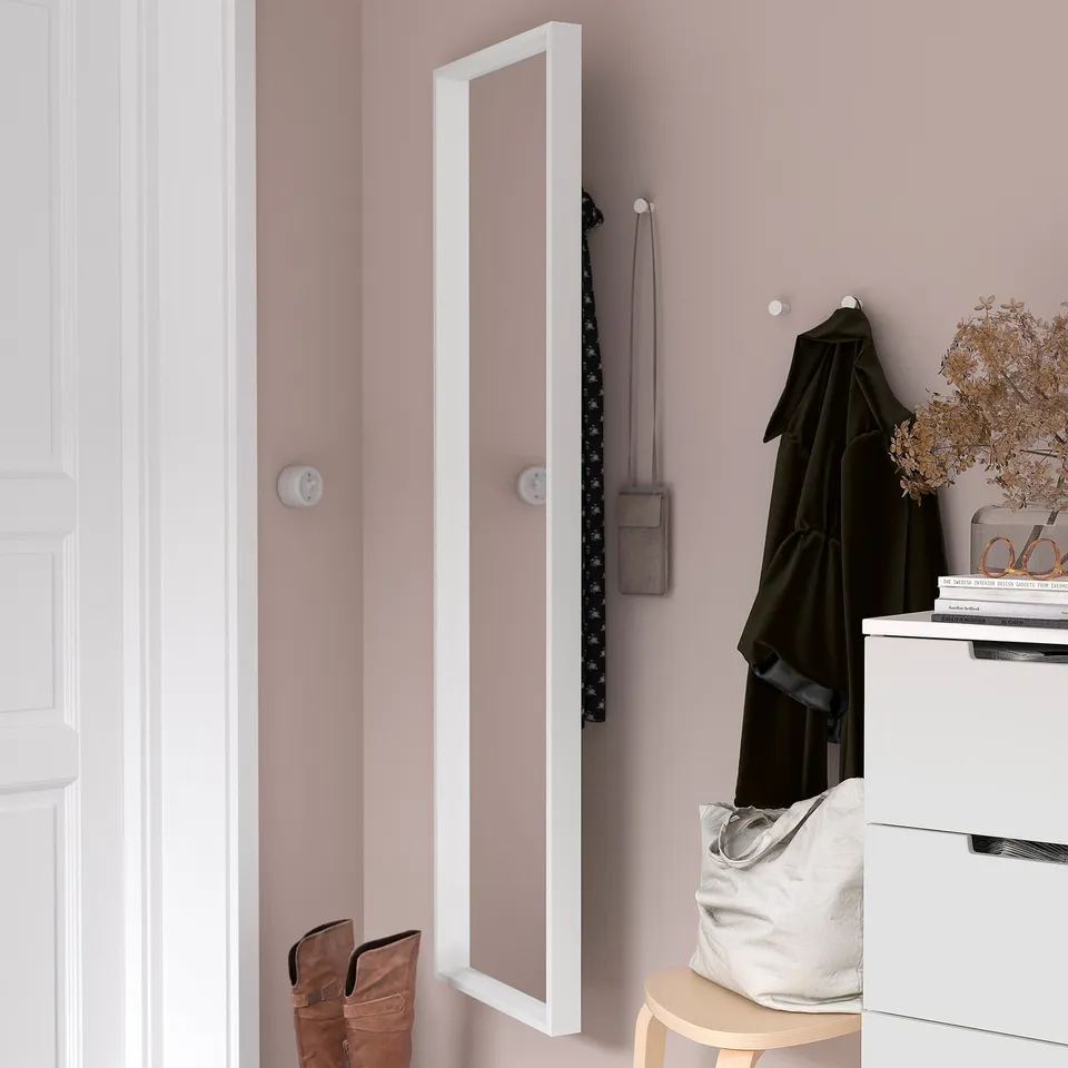 Wall mirror in hallway reflects door, hides coat, bag, and boots.