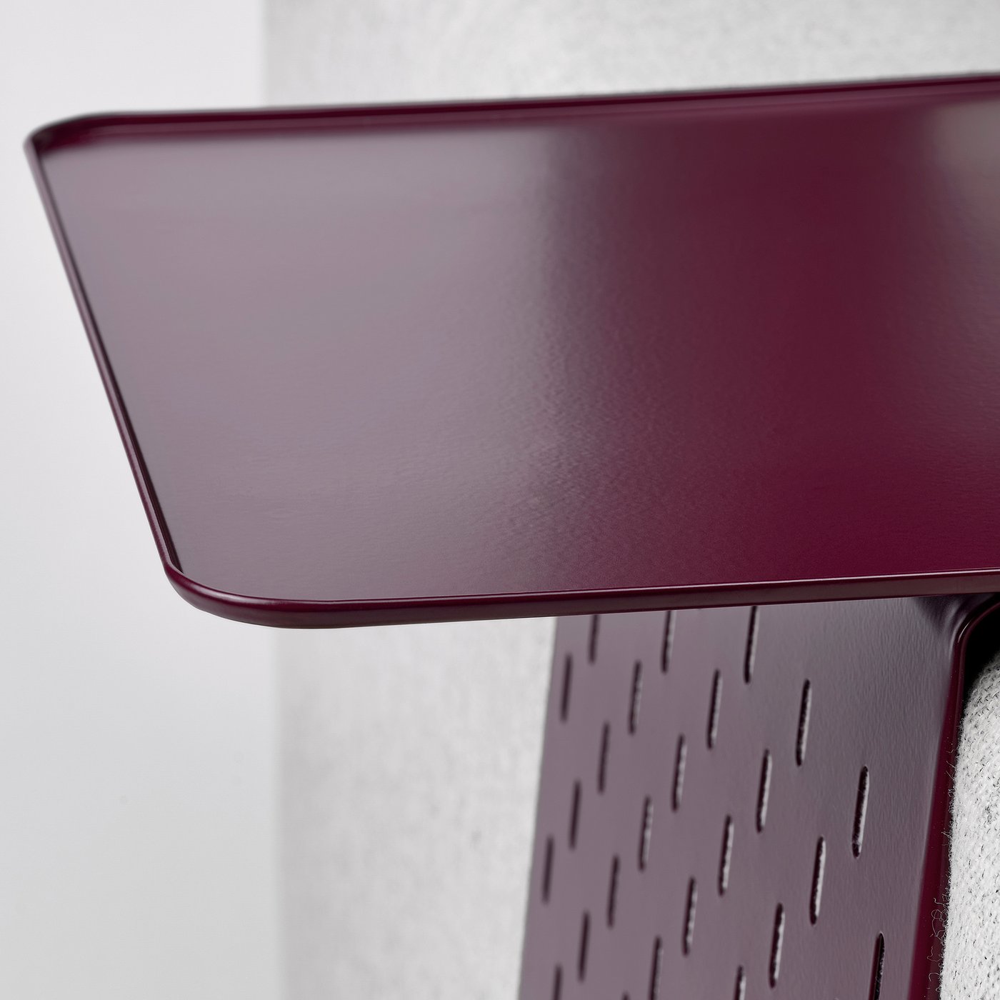 Close-up of maroon metal tray on armrest, smooth surface, perforated edge.