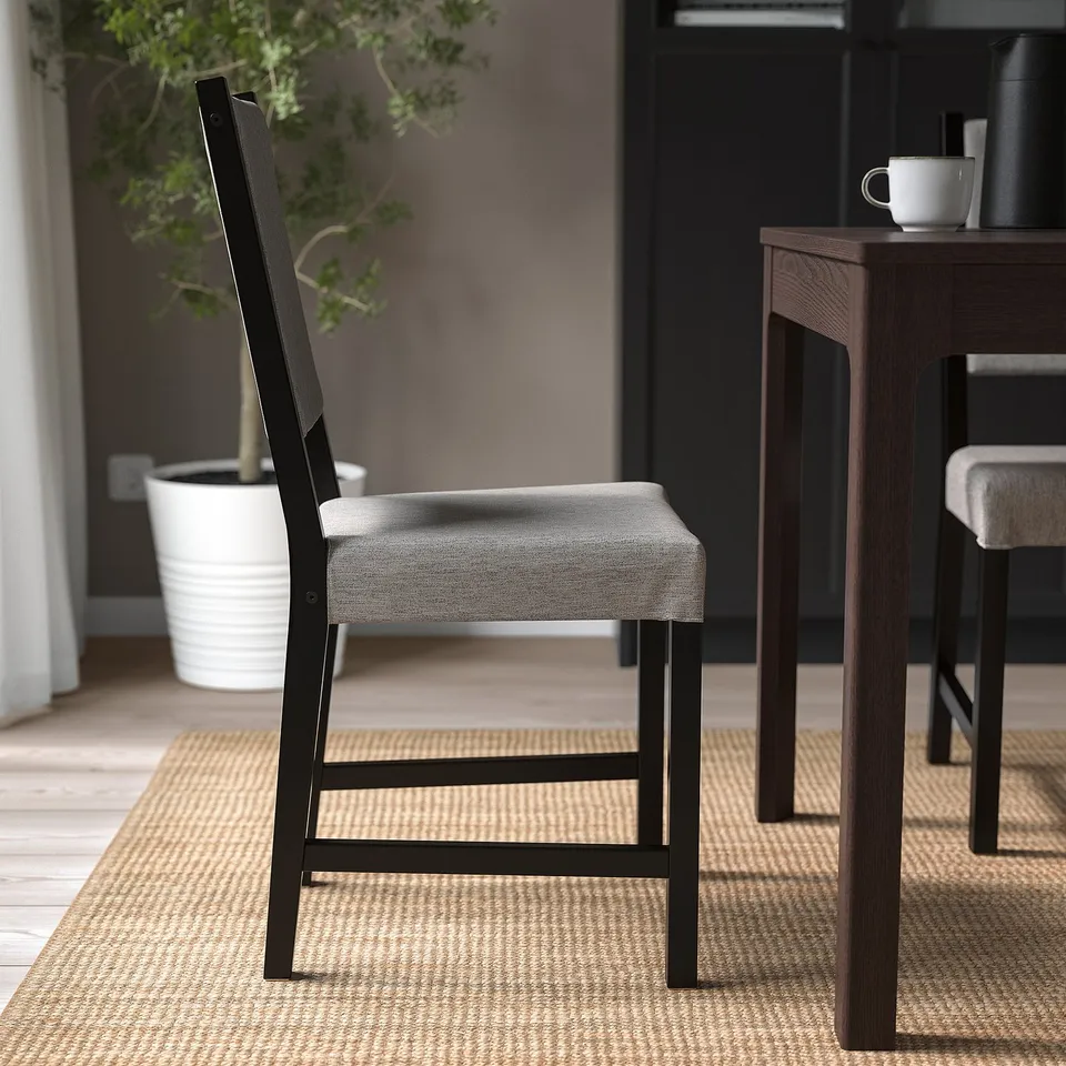 A sturdy, upholstered chair with a solid wood frame sits beside a wooden table on a woven rug. Perfect for indoor comfort.