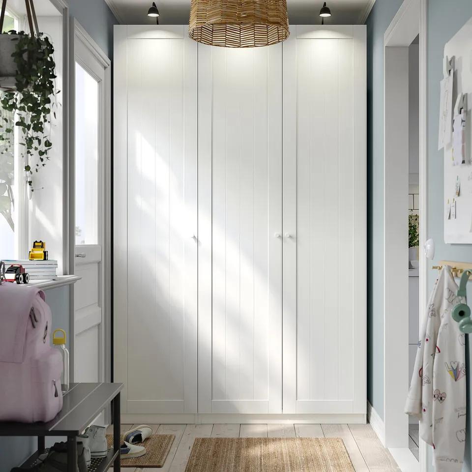 White PAX wardrobe with decor, clean lines, lamp above, handles visible.