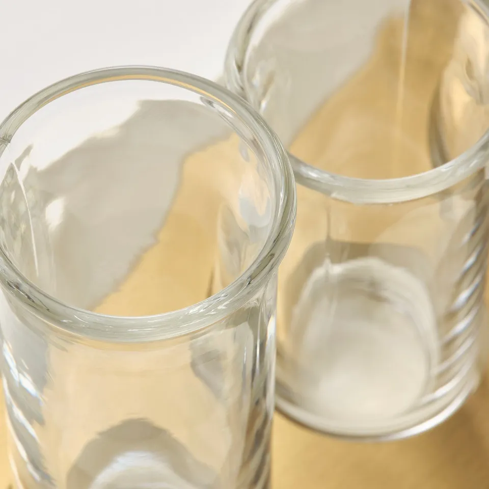 Clear glass vases, reflecting light, standing on golden surface.