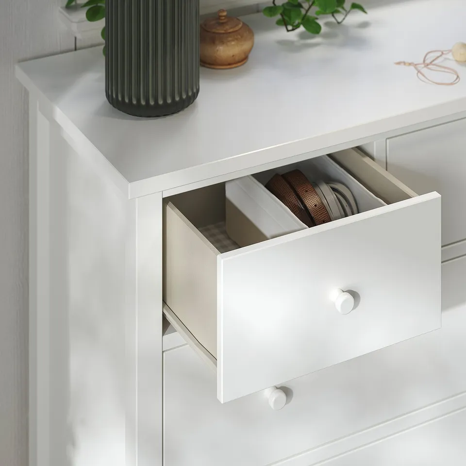 White chest of drawers with smooth-running drawers, one open revealing organisers. Top has vases and plants. High-quality materials and design.