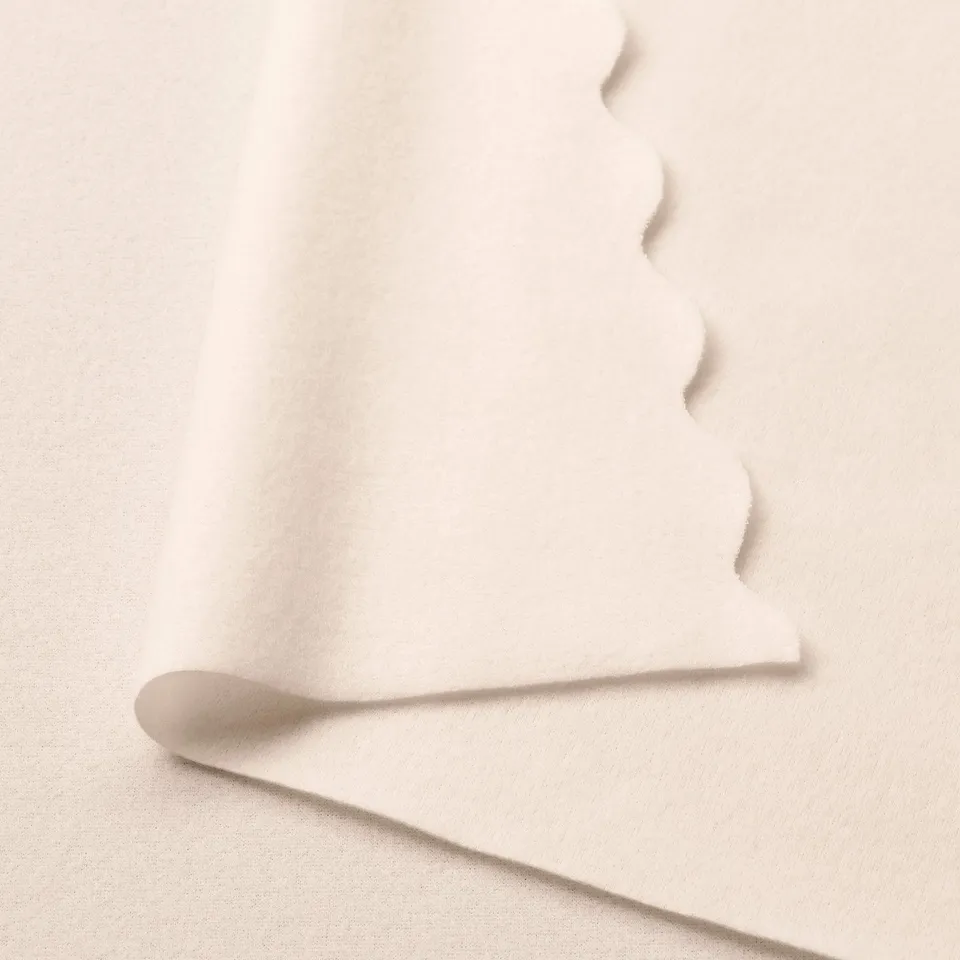 Soft, off-white fleece throw made from eco-friendly recycled polyester, draped elegantly.