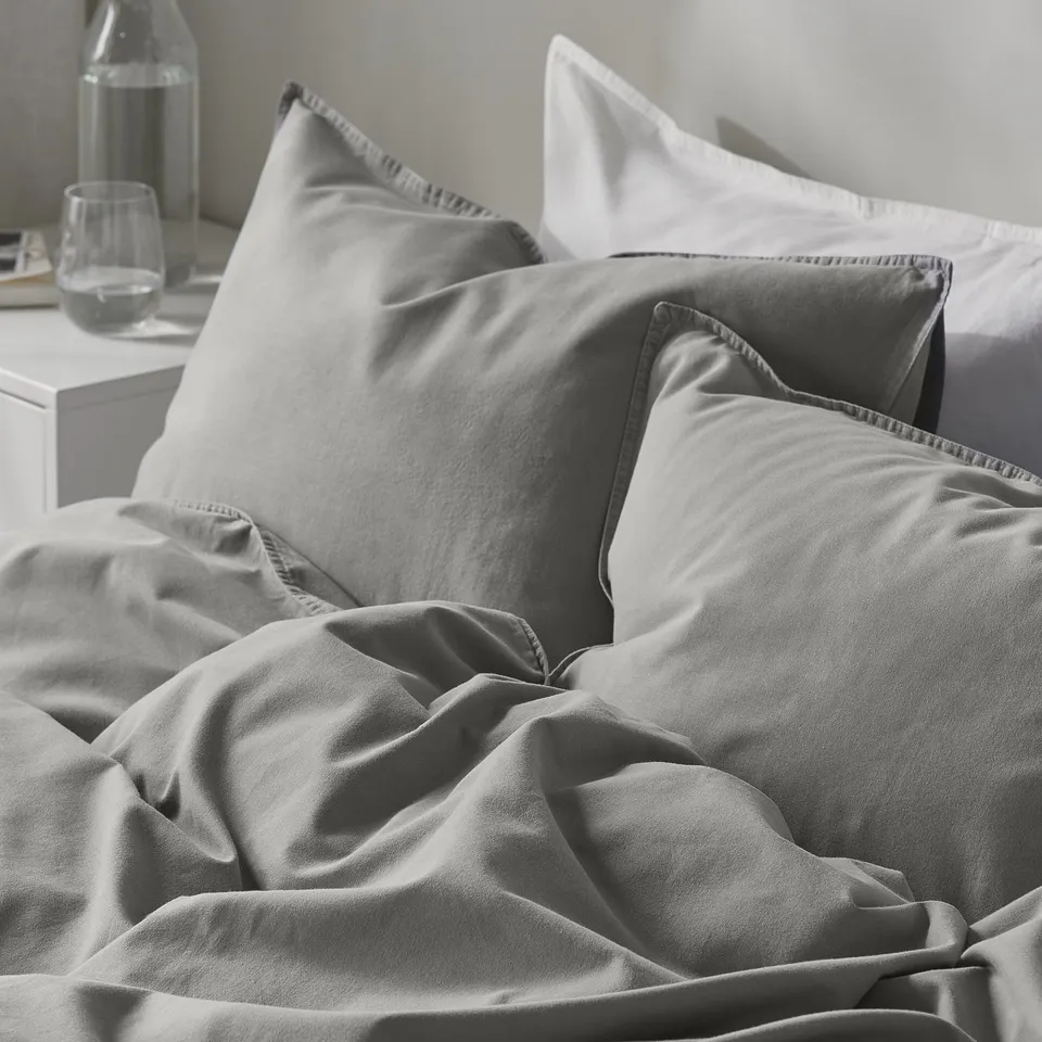 Cosy bed setup with soft, grey ÄNGSLILJA duvet and pillows, showing quality fabric and comfortable design.