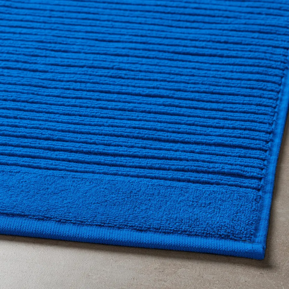 Bright blue textured bath mat, soft and absorbent, made of 100% cotton.