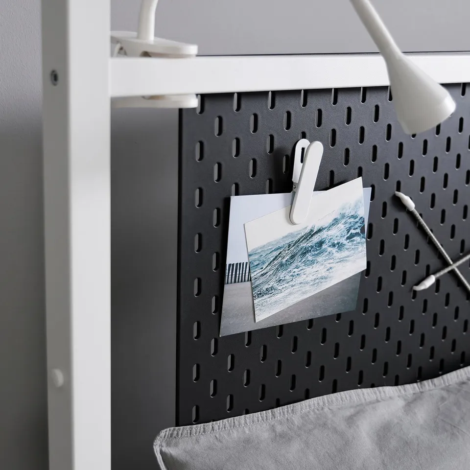 Black pegboard with two clip-on hooks holding a lighthouse.