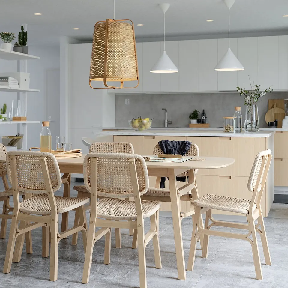 Modern kitchen with VOXLÖV bamboo dining table, beige chairs, pendant lights, and open shelves with decorative items.