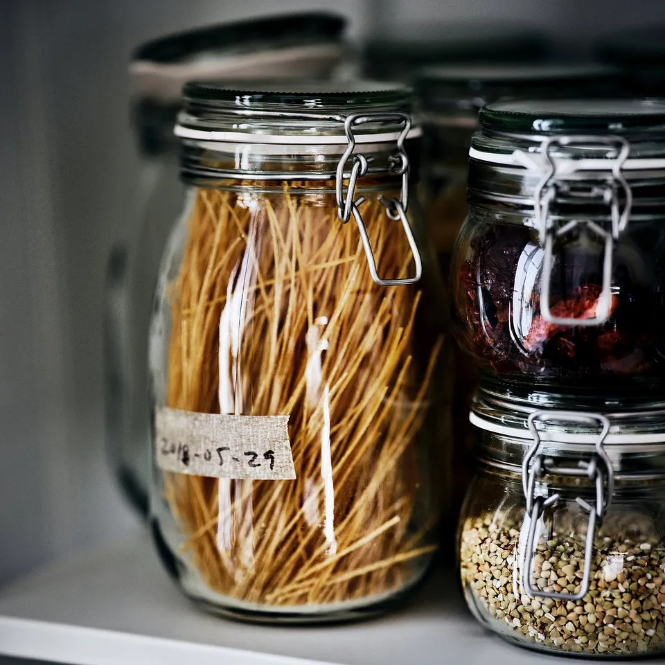 Three sealed jars store dried noodles, seeds, and jam, preserving food freshness.