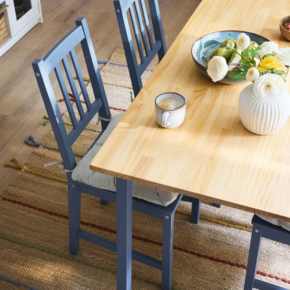 Wooden table with 4 dark blue chairs, flowers, mug