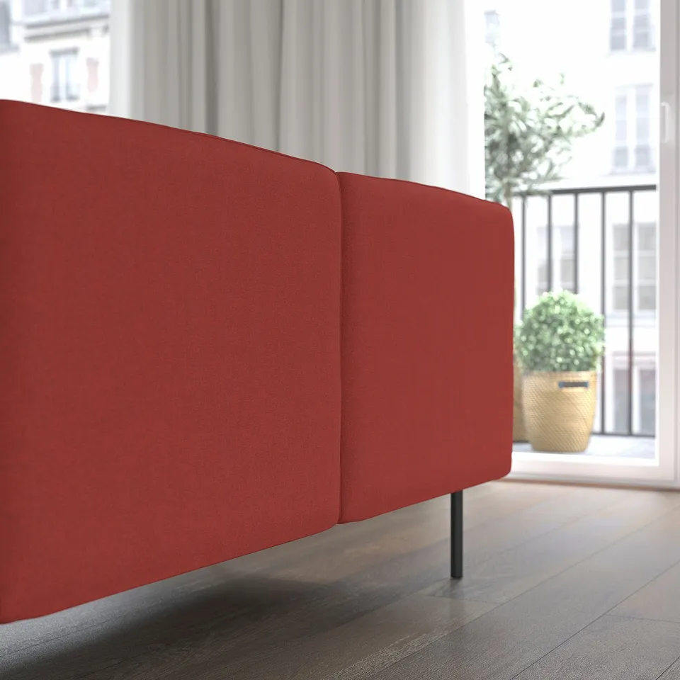Red modular sofa near window, with large potted plant outside.