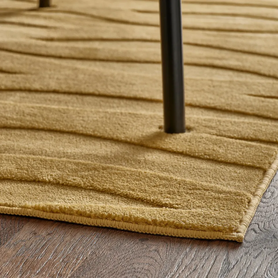 A close-up of a foldable, soft, 3d-patterned yellow-brown rug, with a non-slip backing.