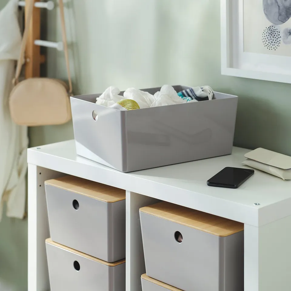 White storage box on shelf, holds miscellaneous items, stacks with other boxes.