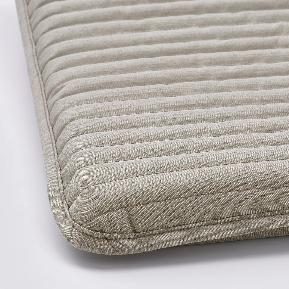 Close-up of a plush, textured cushion with meticulous stitching. Soft, ribbed fabric suggests comfort.