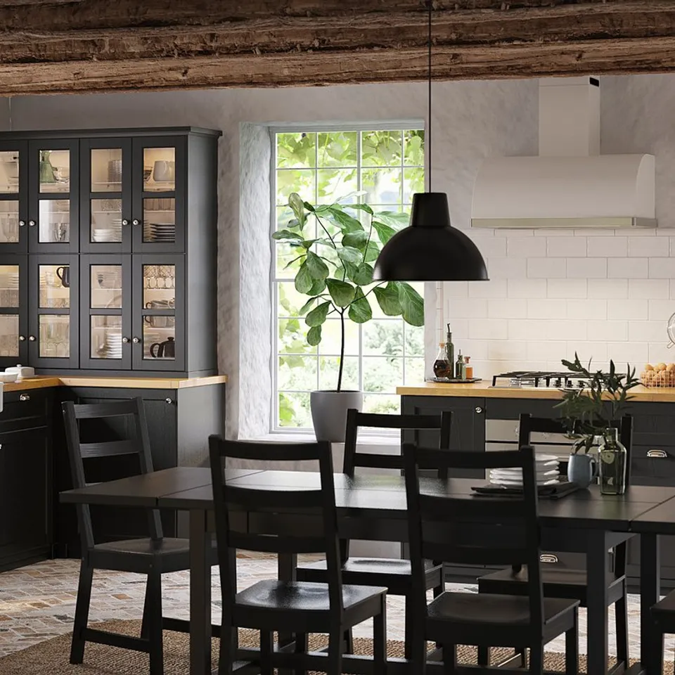Modern farmhouse kitchen: black stained cabinets, wooden countertop, stainless steel appliances, hanging lights, wooden chairs.