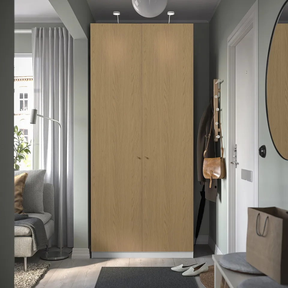 Modern wooden PAX wardrobe in entryway with mirror, shoe rack, and bags.