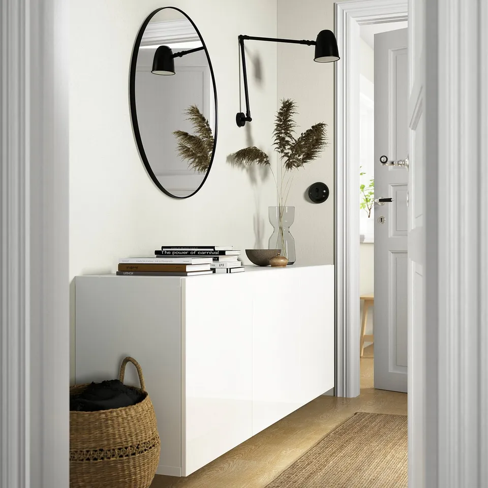 White BESTÅ unit with books, decor, and mirror.
