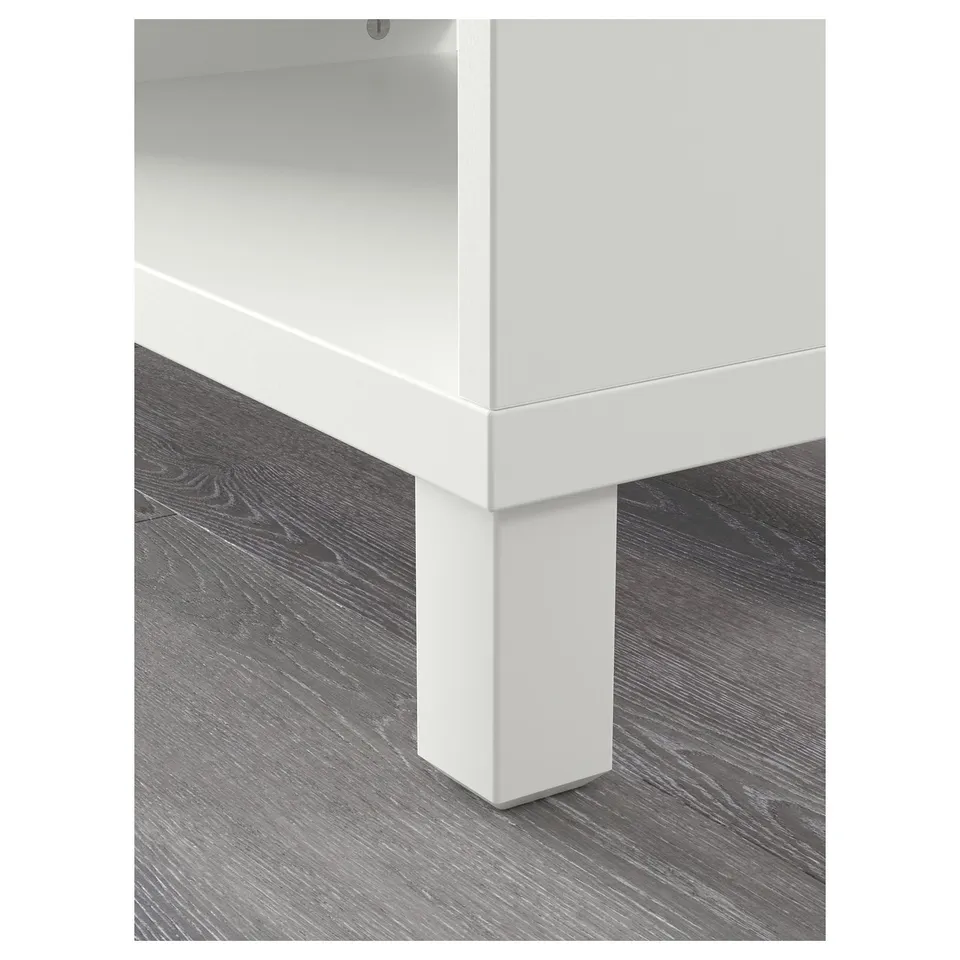 White, modern, corner of a BESTÅ shelving unit. Shows clean lines, sturdy white legs, and a spacious open shelf.