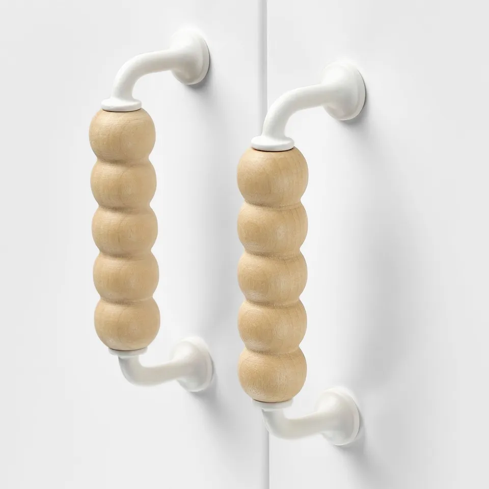 Modern wooden knobs with smooth, light birch finish and durable white metal handles affixed to a clean white surface.