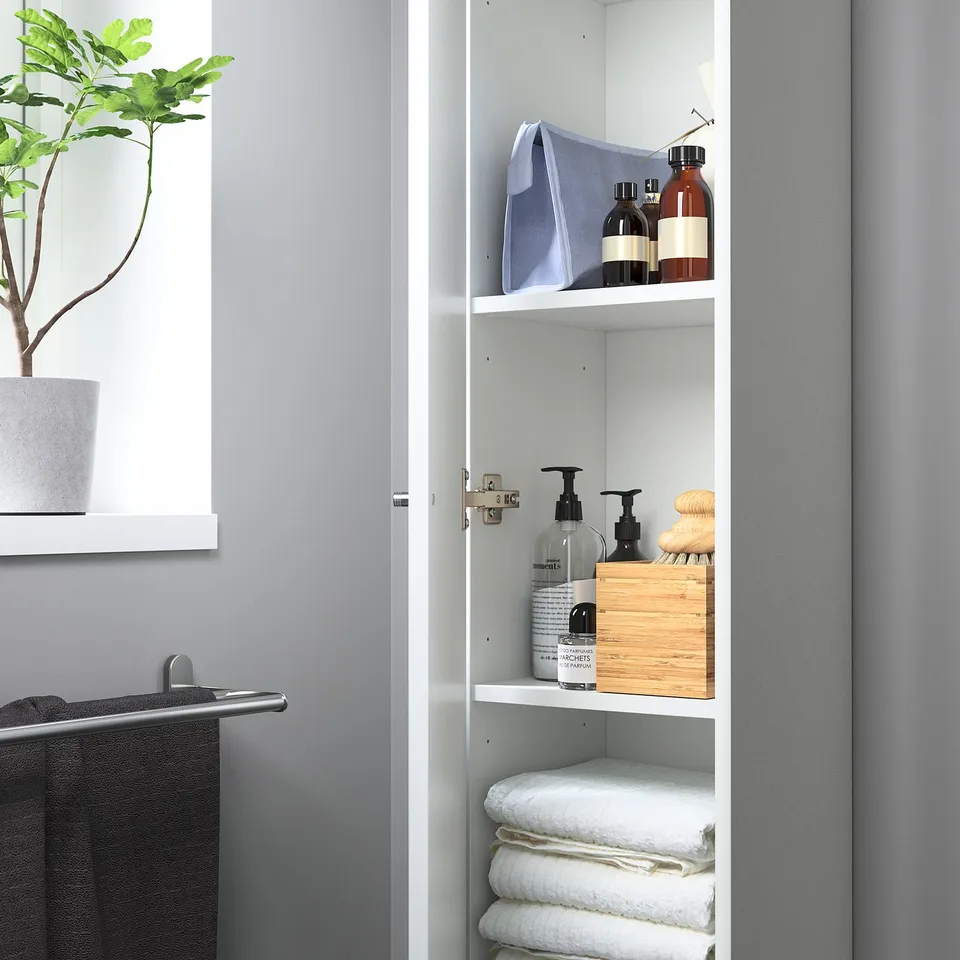 Open cabinet with sections: folded towels, toiletries, wood box, bottles.