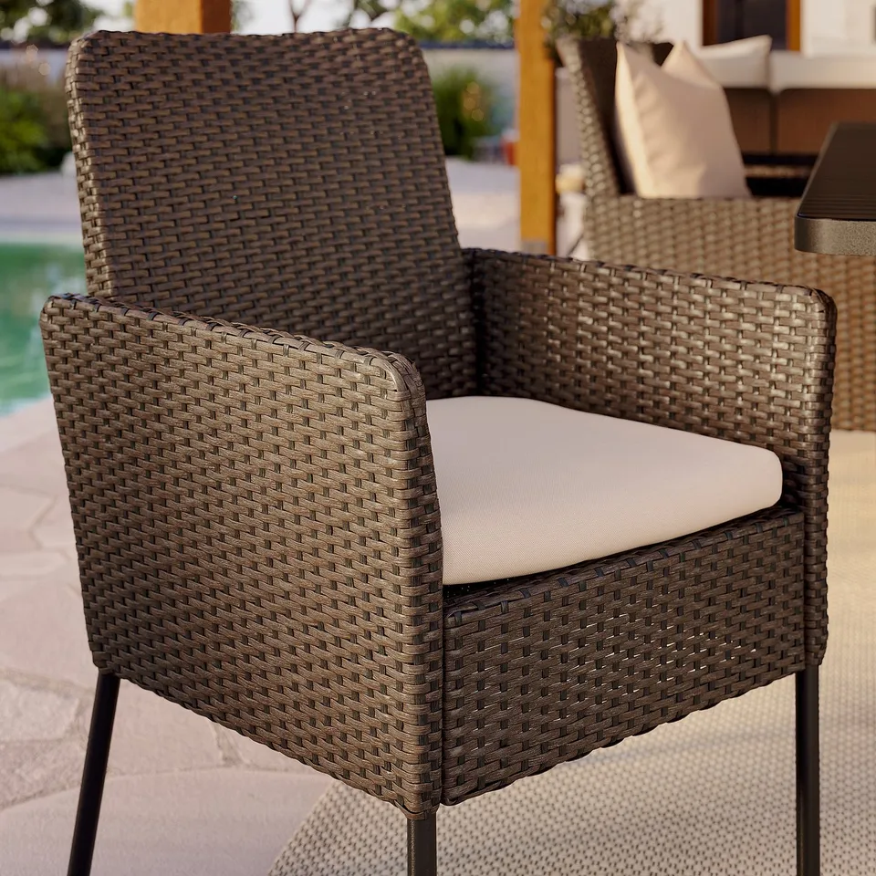 Durable outdoor chair with woven wicker and beige cushion, perfect for relaxing.