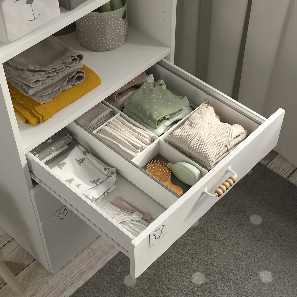 Nursery bookcase with open shelves & drawers for baby clothes & essentials.